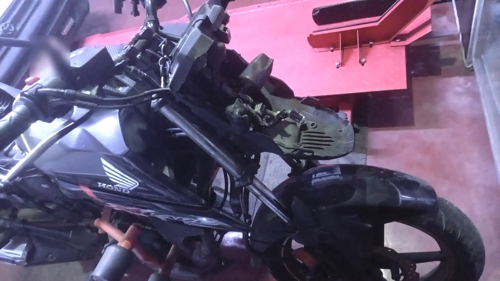 Moto Honda sin carenados sobre el elevador del taller