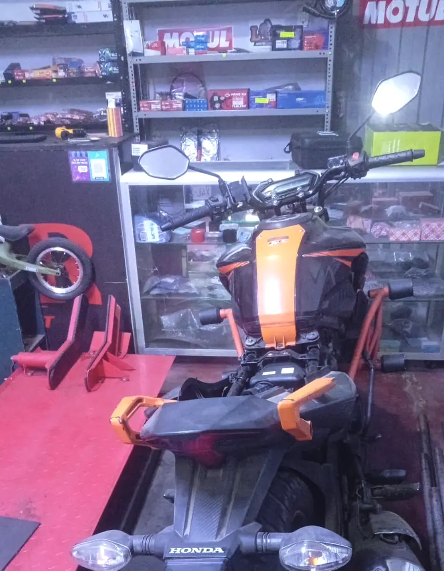 Moto sobre el elevador del taller, con el mostrador de repuestos detrás